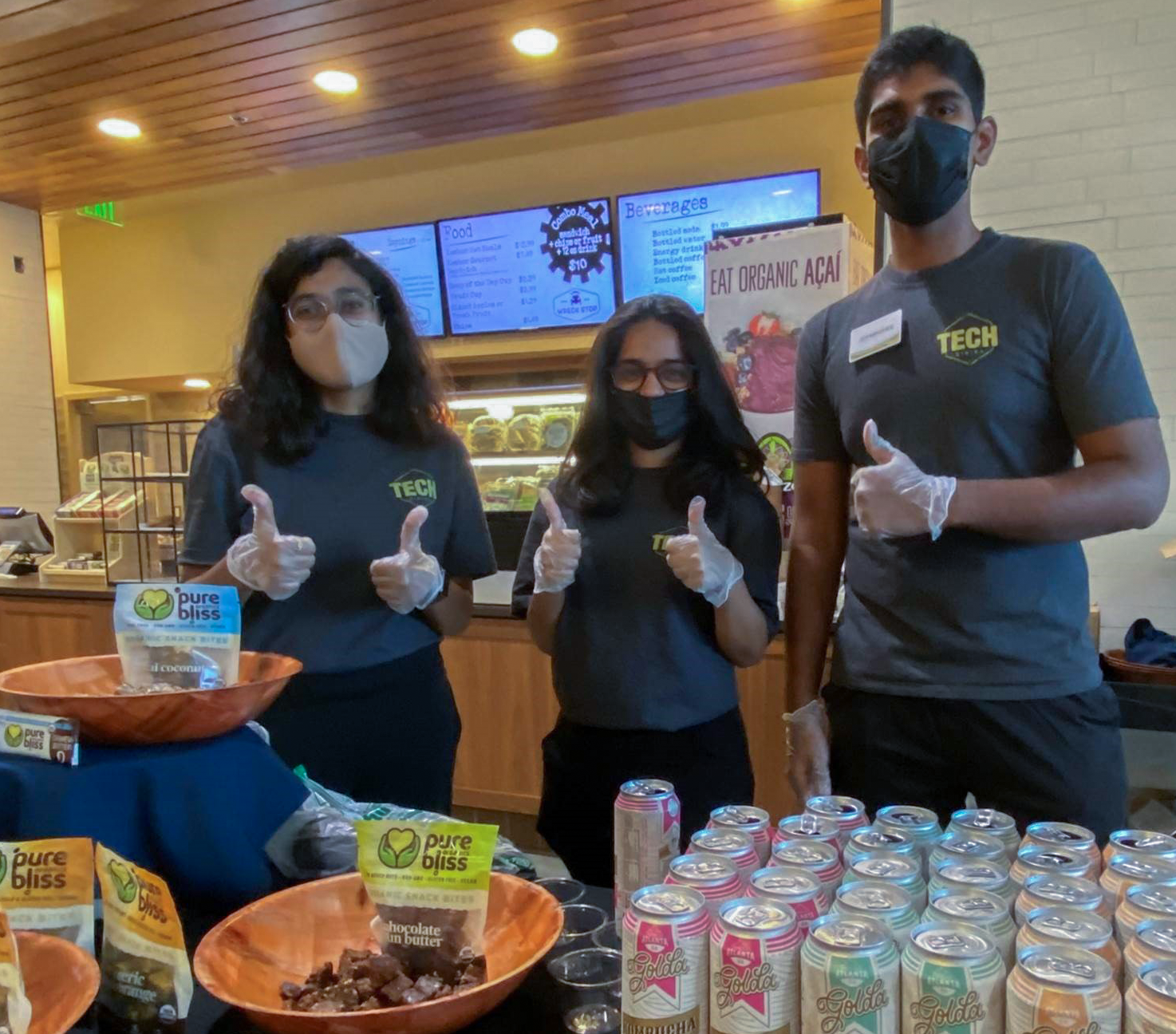 3 students giving thumbs up by food display